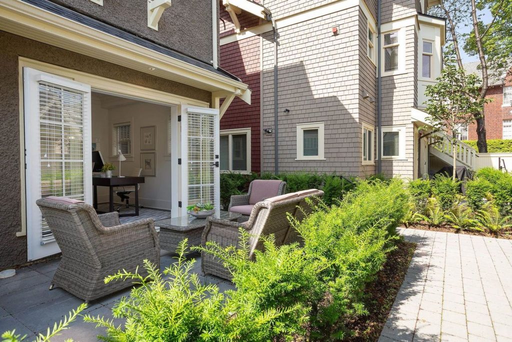Exterior shot showing back patio with French doors leading from flex office space.